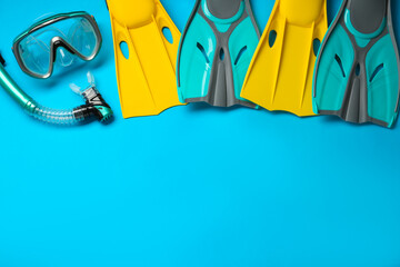 Different flippers and mask on light blue background, flat lay. Space for text © New Africa