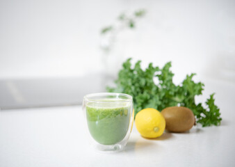 Kale smoothie in a glass on mable countertop