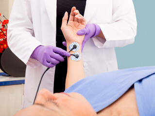 Mujer en revisión médica con sensores en la mano y doctor atendiendo su estado de salud en una clínica de atención médica - obrazy, fototapety, plakaty