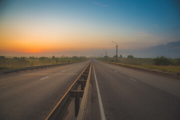 the multi-lane road goes into the distance and gets lost in the predawn haze