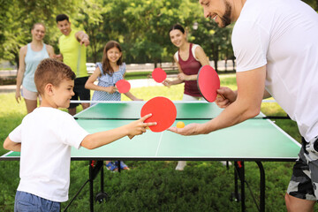 Happy family playing ping pong in park