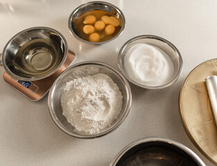 general view of a table with metal bowls with eggs, flour, sugar and more baking ingredients