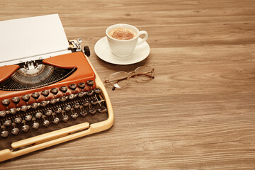 Obraz na płótnie Canvas Vintage typewriter, glasses and cup of coffee on wooden table. Space for text