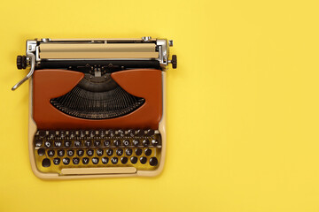 Vintage typewriter on yellow background, top view. Space for text