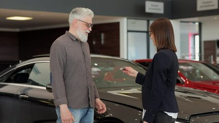 Woman manager in glasses gives car key to senior client Spbi