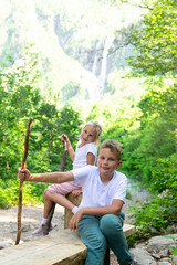 Happy children on a hike in the mountains. Children on a mountain walk with sticks.
