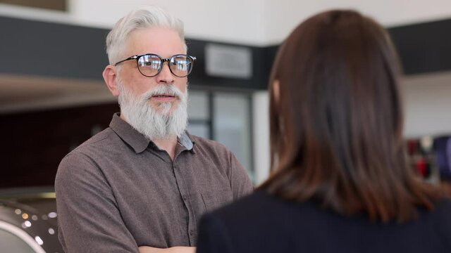 Showroom car, saleswoman and elder man client discuss car options, middle shot face close up. Spbi