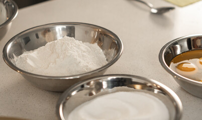Three metal bowls with flour, sugar, and eggs