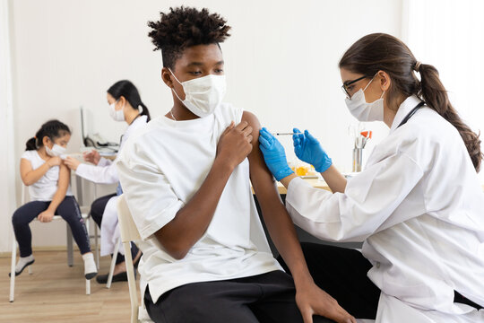 young male african wearing medical face mask and getting vaccinated from doctor, to build up or maintain immunity