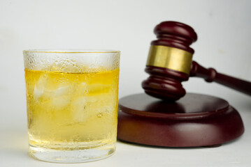 Alcohol offenses concept.Glass of whiskey with gavel hammer background.