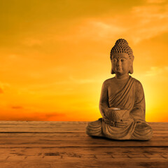 Beautiful stone Buddha sculpture on wooden surface at sunset. Space for text