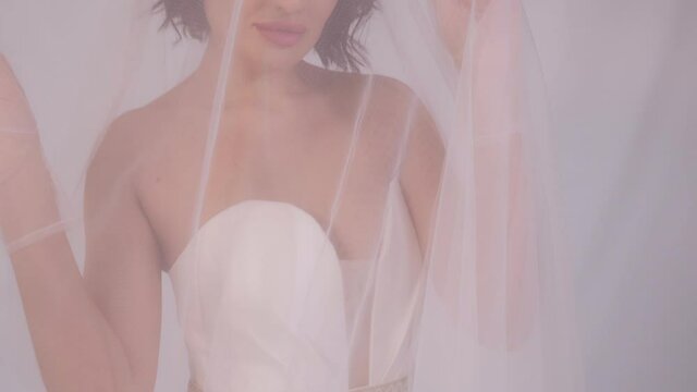 Portrait of a bride with a long veil, her head and face are covered with a veil.