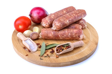 Raw homemade pork sausages laid out with spices on a round wooden board, isolated on a white background.Selective focus.top view.