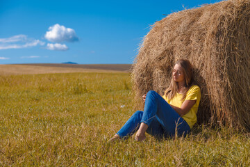 Naklejka na ściany i meble a girl is sunbathing in the hay. village life: harvesting hay for the winter. animal feed.