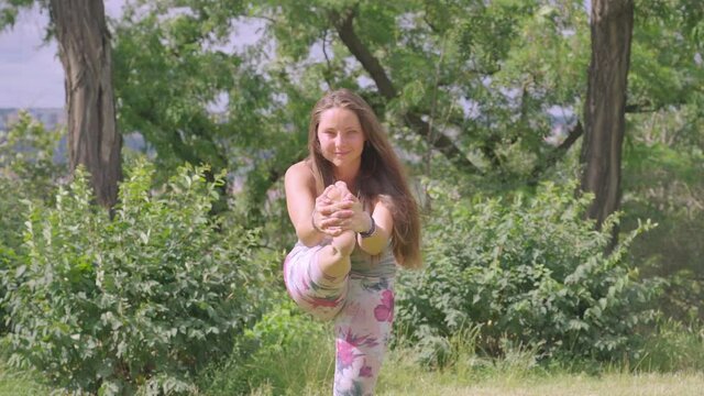 Caucasian woman doing yoga position on green field in nature. outdoor sport, stretching body