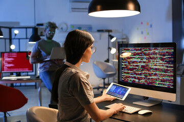 Female programmer working with computer in office at night