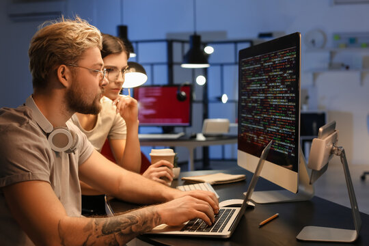 Young programmers working with computer in office at night