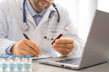 Doctor while working in his office. He is in charge of describing a blood sample in a test tube....