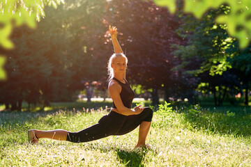 Yoga. Young woman practicing yoga or dancing or stretching in nature at park. Health lifestyle concept