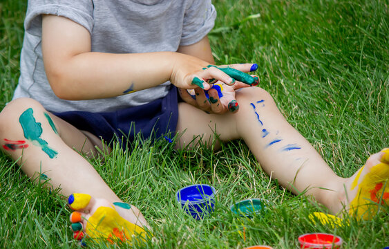 The child draws a pattern on the leg. A funny drawing with bright colors on the body.
