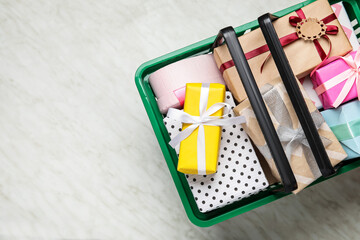 Shopping basket with gift boxes on white background