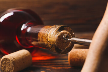 Bottle of exquisite wine with corkscrew on wooden table, closeup