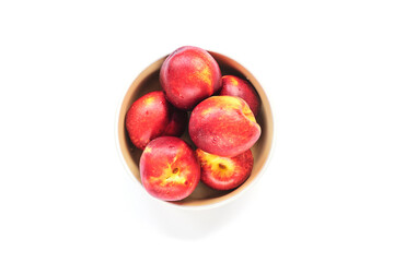 Ripe red peaches in a bowl isolated on white. Top view, flat lay
