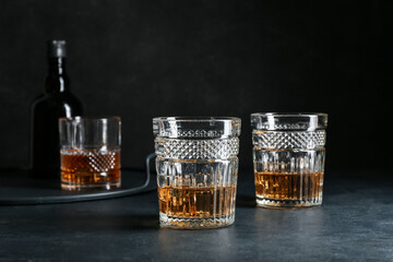 Glasses of cold whiskey on dark background