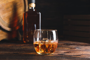 Glass of cold whiskey on dark wooden background