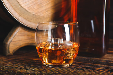 Glass of cold whiskey on wooden background