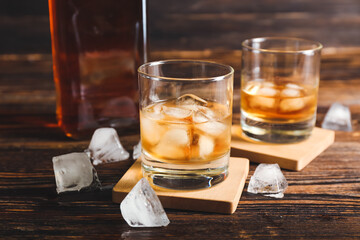 Glasses of cold whiskey on wooden background