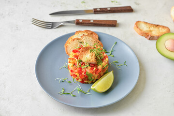 Plate with tasty tartare salad on light background
