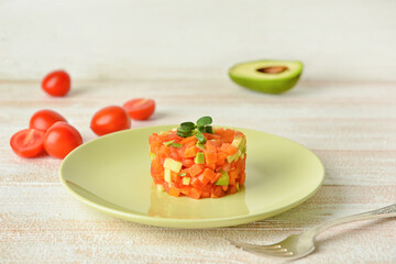 Plate with tasty tartare salad on light wooden background, closeup
