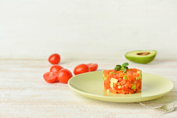 Plate with tasty tartare salad on light wooden background
