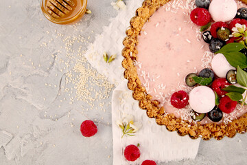 Strawberry vanila tart topped with berries on light gray background.