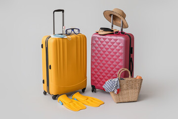 Packed suitcases with immune passport, medical masks and beach accessories on grey background