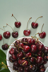 Fresh cherries in a bowl in bowl on green background.