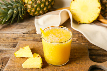 Glass of tasty pineapple smoothie on wooden background