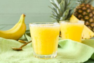 Glasses of tasty pineapple smoothie on color wooden background, closeup