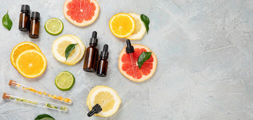 Bottle of essential aroma oils with citrus on light gray background.