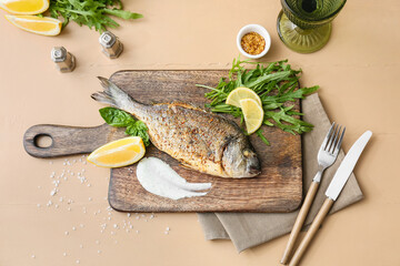 Wooden board with fried dorado on color background