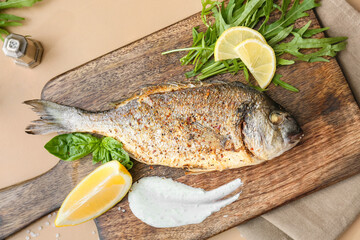 Wooden board with fried dorado on color background