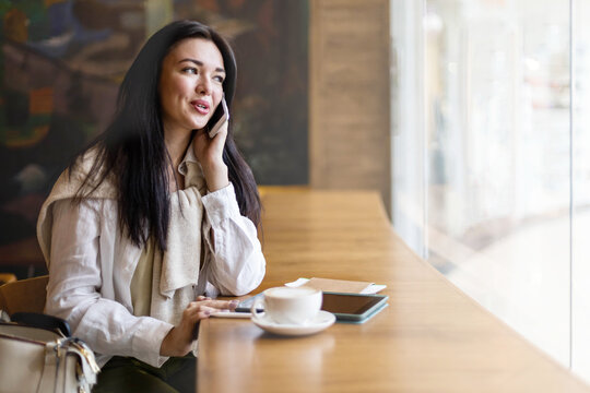 Happy woman sitting at cafe waiting departure flight in airport terminal talking use smartphone