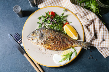Plate with fried dorado on color background