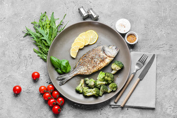 Plate with fried dorado and vegetables on grunge background