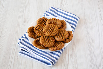 Homemade Peanut Butter Cookies on a plate on a white wooden background, side view.