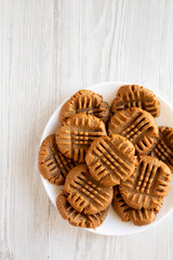 Homemade Peanut Butter Cookies on a plate on a white wooden surface, top view. Flat lay, overhead, from above. Copy space.