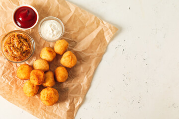 Fried potato balls and different sauces on light background
