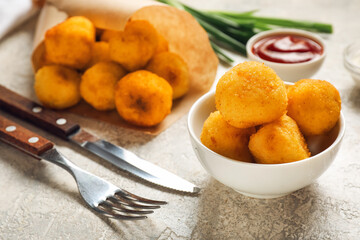Bowl with fried potato balls on grunge background