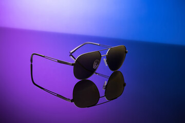 Black sunglasses on blue reflective surface, closeup. Product photography and fashion concept